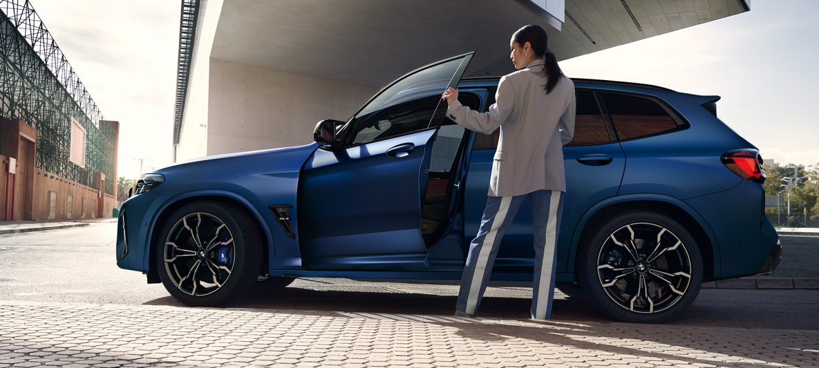 BMW X3 M Competition F97 LCI Facelift 2021 Frozen Marina Bay Blau metallic Seitenansicht mit geöffneter Tür und weiblichem Model